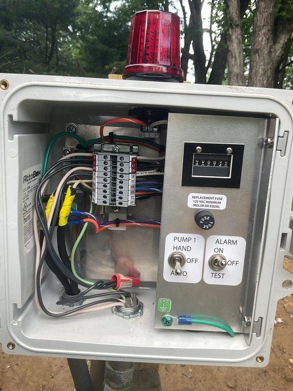 Responded to callback for ongoing alarm system issues with GFI breaker tripping. Inspected outdoor electrical control panel containing pump and alarm float switch controls with digital counter and manual override switches. Reviewed wiring diagram and verified connections at terminal strip, examining multi-conductor wiring routing and grounding. Customer reported alarm malfunction recurring immediately after previous service visit and requested proper outlet box installation without silicone sealing method used previously.