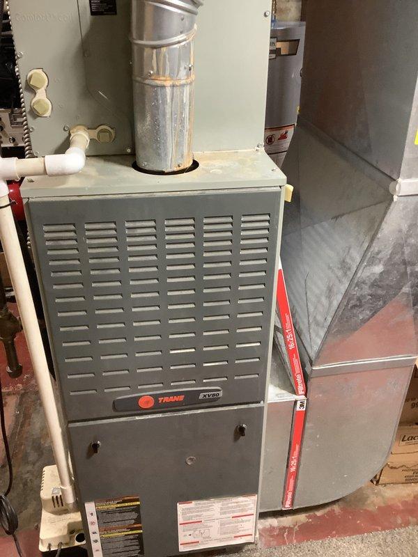Conducted on-site assessment of 20-year-old residential HVAC system for air conditioner and furnace replacement estimate. Evaluated existing Trane XV80 furnace installation in basement utility area, including combustion air intake piping, ductwork connections, and venting configuration. Inspected exterior air conditioning unit, electrical disconnect box, and conduit routing along building exterior to determine replacement requirements and specifications.