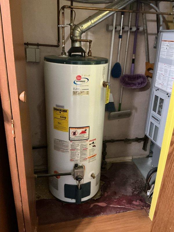 Responded to active water leak in utility room of 76-year-old residence. Upon inspection, found existing Rheem Fury gas water heater (installed 5-27-07) with visible leaking at tank base causing water accumulation on concrete floor. Due to age of unit (17+ years) and active tank failure, recommended and performed complete water heater replacement. Removed failed unit, installed new gas water heater with proper venting connections, reconnected copper supply lines and gas line, and tested all connections for leaks. Verified proper operation of new unit and cleaned work area.