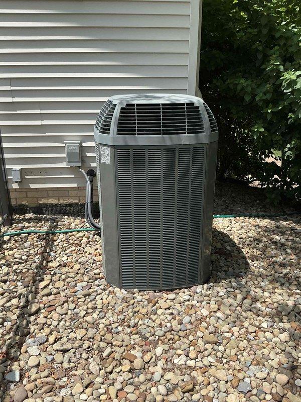 Provided estimate for complete air conditioning system replacement due to refrigerant leak in existing 13+ year old unit. Assessed outdoor cylindrical condenser unit with tower-style configuration and corresponding indoor HVAC equipment including furnace and air handler located in basement utility area. Documented existing system conditions with photographs showing equipment age, installation configuration, and leak source to support replacement recommendation rather than repair given unit age and refrigerant loss.
