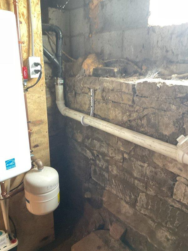 Excavated and exposed broken clay main drain line in basement dirt floor, rerouting drainage system around existing furnace to main stack. Installed new PVC piping from exposed clay section to copper main stack connection, ensuring proper pitch and alignment. Reworked kitchen drain line underground with appropriate pitch and tied into new drainage system. Hand-dug trenches to access deteriorated clay piping, installed new pipe on gravel bed, and backfilled excavated areas with original soil upon completion.