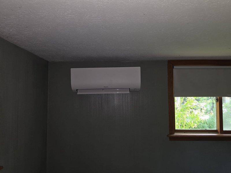 Completed installation of a two-head ductless mini-split system in a brick residence. Mounted indoor air handler units in two separate rooms with wood-paneled and standard wall finishes, ran refrigerant lines and electrical connections between outdoor condenser and indoor units, and concealed all line sets using appropriate line hide covers for a clean, professional appearance. All components tested and operational upon completion.