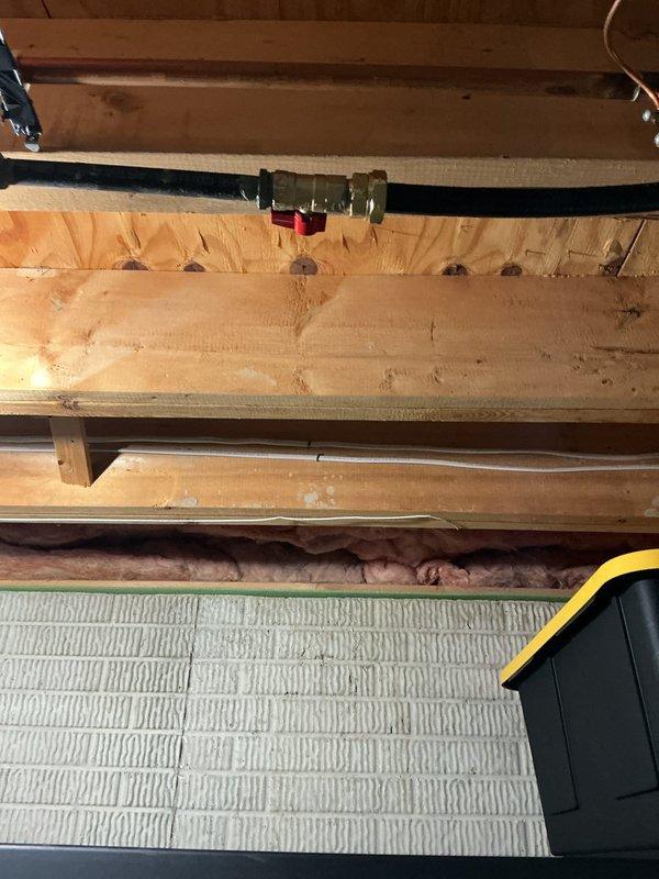 Completed tankless water heater installation in basement utility area, including core drilling for proper venting and exhaust pipe routing through structural framing. Installed unit with Navien recirculation kit, ran new gas and water supply lines, and secured all piping and venting components per manufacturer specifications. System tested and verified operational with proper combustion air flow and venting clearances confirmed.