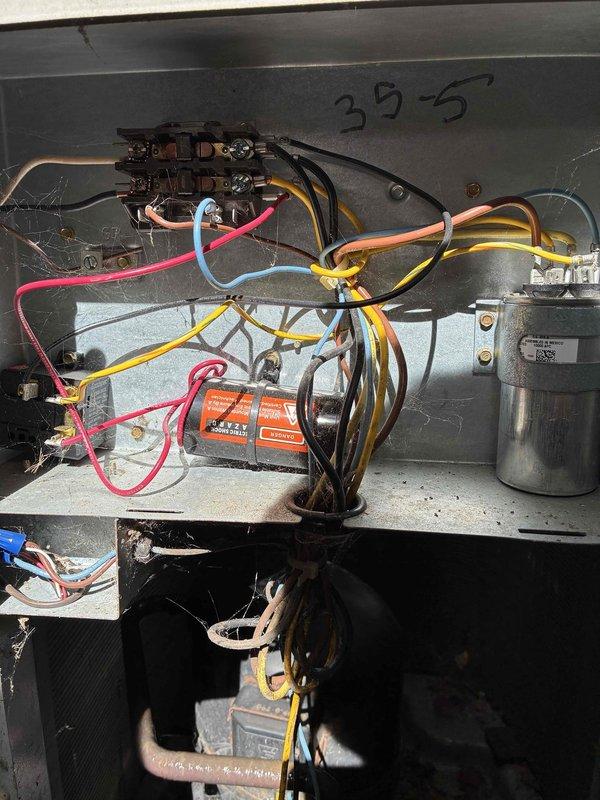 Performed maintenance inspection on 27-year-old Carrier outdoor condensing unit. Unit showed significant age-related wear with weathered housing, dirt accumulation on fan grille, and vegetation growth around base perimeter. Accessed electrical compartment and inspected internal wiring, connections, and components including capacitor and motor assembly. All electrical connections were verified secure at terminal blocks. Unit remains operational despite advanced age, though replacement should be considered due to system age exceeding typical service life expectancy.