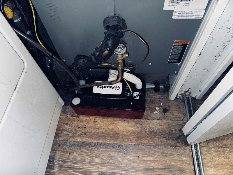 # HVAC Service Report - Water Leak Resolution

Responded to service call for persistent water leak on 5-year-old air conditioning system that continued following previous service visit. Upon arrival, conducted thorough inspection of the indoor air handler unit and associated drainage components.

Inspection revealed condensate pump assembly located in utility closet with Asurity brand pump mounted on base platform. Observed signs of water damage on wooden flooring surrounding equipment, indicating ongoing moisture issues. Examined all condensate drain lines, including copper tubing and flexible drain hoses connected to pump assembly.

Identified compromised condensate drainage system as source of leak. Tested condensate pump operation and verified pump functionality. Inspected drain pan for cracks, proper pitch, and blockages. Checked float switch operation and electrical connections to pump assembly.

Cleared condensate drain lines of any debris or biological growth that could restric