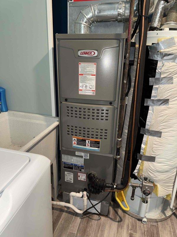 Responded to service call for condenser running continuously and evaporator coil leaking water onto utility room floor. Upon inspection, found Lennox furnace system with active condensate drainage issues causing water accumulation on floor. Documented existing PVC condensate drain line configuration and furnace installation with photographic evidence. Contacted property owner to report findings and discuss necessary repairs to address coil leak and condenser operation concerns.