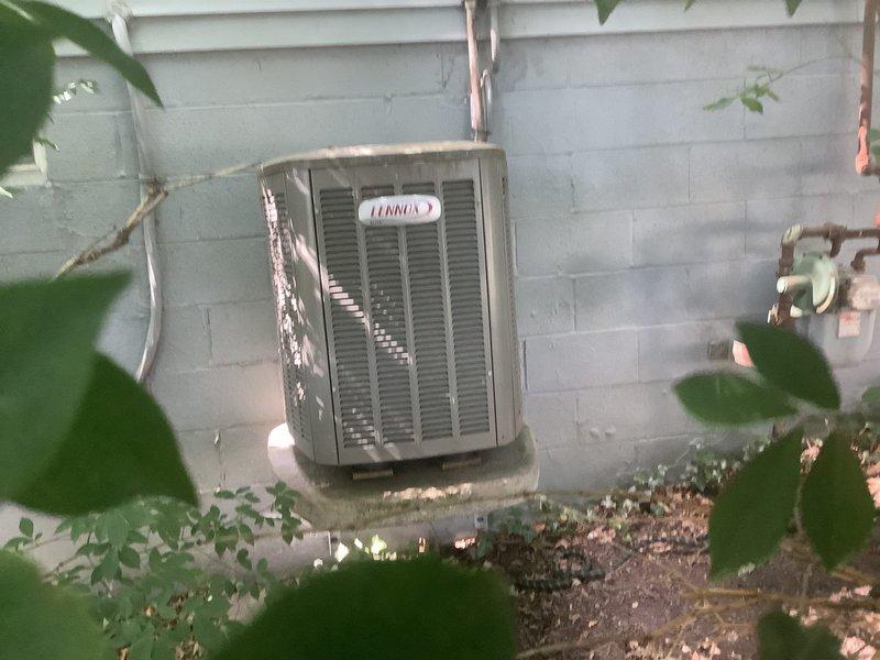 # No Cooling - Debris Accumulation in Condenser Unit

Responded to service call for Lennox air conditioning system running but not cooling with indoor temperature at 84°F. Upon arrival, performed visual inspection of outdoor condenser unit and found electrical panel accessible. Discovered significant accumulation of organic debris, including dried plant material and twigs, in lower compressor section and around internal components. Debris accumulation appeared to be nest material from rodents or birds that had built up over time, restricting airflow and potentially affecting system operation.

Removed electrical panel covers and thoroughly cleaned out all organic debris from compressor area and electrical compartment. Inspected capacitor, contactors, and relay switches for damage or deterioration caused by debris and wildlife activity. Verified all electrical connections were secure and free from corrosion. Checked refrigerant lines running along exterior wall for any damage or restric