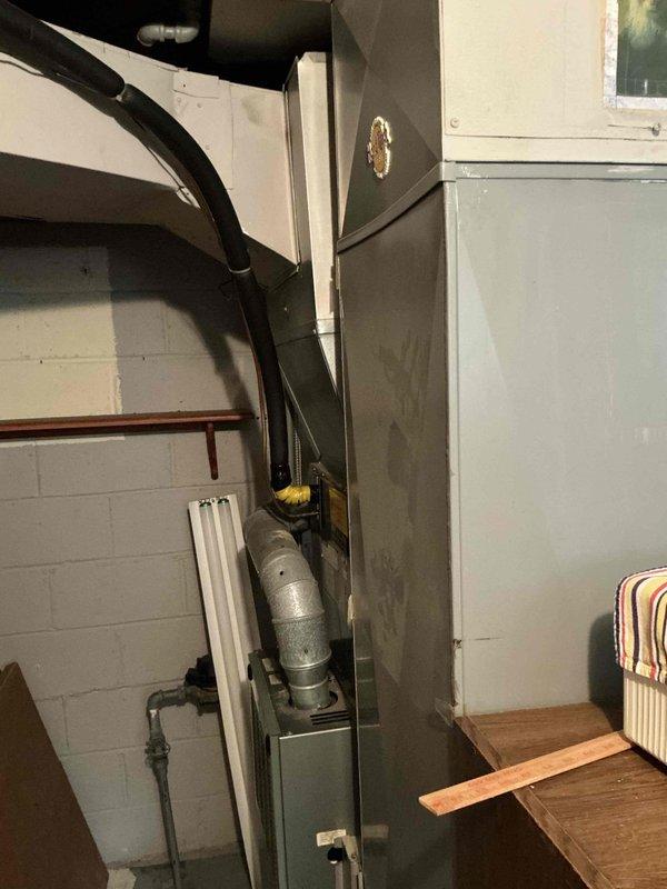 Completed comprehensive estimate for replacement of 30-year-old gas furnace and air conditioning system. Assessed existing outdoor condenser unit positioned on concrete pad against brick exterior wall and indoor furnace unit located in basement utility area with associated ductwork and venting systems. Documented current equipment condition, measured existing installation specifications, and photographed both interior and exterior components to provide accurate replacement recommendations for aging HVAC system nearing end of service life.