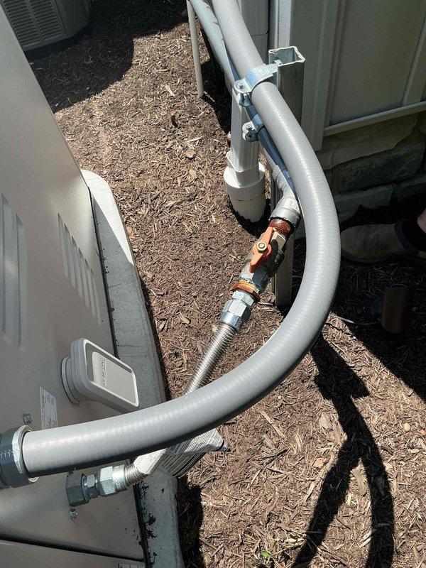 Responded to service call regarding reported gas odor near recently installed 22kW natural gas standby generator. Upon arrival, customer reported detecting gas smell around unit over the weekend, which dissipated after shutting down the generator. Performed thorough inspection of generator installation, gas connections, and surrounding area. No active gas leaks detected at generator unit, gas line connections, or supply piping. Verified all gas fittings were properly torqued and sealed. Inspection revealed HVAC refrigerant lines with copper coupling connections in close proximity to generator location. Determined gas odor was unrelated to generator installation. Documented site conditions with photographs showing generator area, exterior utility installations, and equipment placement. Advised customer that issue was not associated with generator system and unit could be safely returned to service.