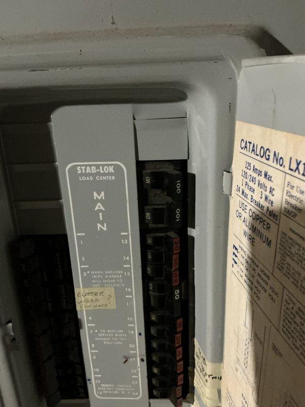 Performed comprehensive HVAC system evaluation for 47-year-old air conditioning system located in basement utility area. Assessed existing beige air handling unit with metal ductwork configuration, documented electrical panel condition showing older Stab-Lok load center with signs of age, and provided replacement estimate for complete system upgrade due to equipment age exceeding typical service life expectancy.