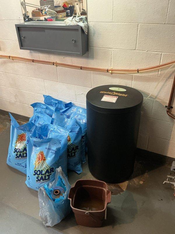 Delivered eight bags of solar salt for water softener system as part of recurring maintenance service. Restocked salt supply in utility room adjacent to water treatment equipment, which included a water softener unit with digital control panel displaying hardness setting of 30 grains. Verified proper placement of salt bags near treatment system for customer accessibility.
