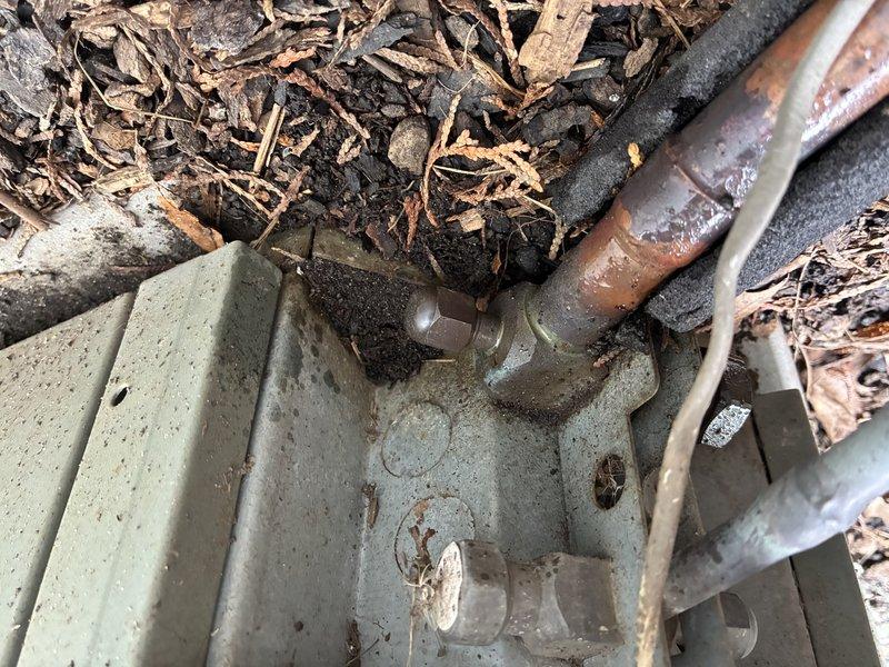 Completed comprehensive AC tune-up and system inspection. During the service, identified severe corrosion and deterioration on electrical connections within the outdoor disconnect box, including heavily rusted terminals, corroded mounting plates, and degraded wire connectors indicating prolonged moisture exposure. Inspected refrigerant line set penetrations at foundation level, noting weathered line insulation and copper piping with natural patina from outdoor exposure; confirmed proper line set routing through landscaping area with adequate mulch coverage for ground contact protection.