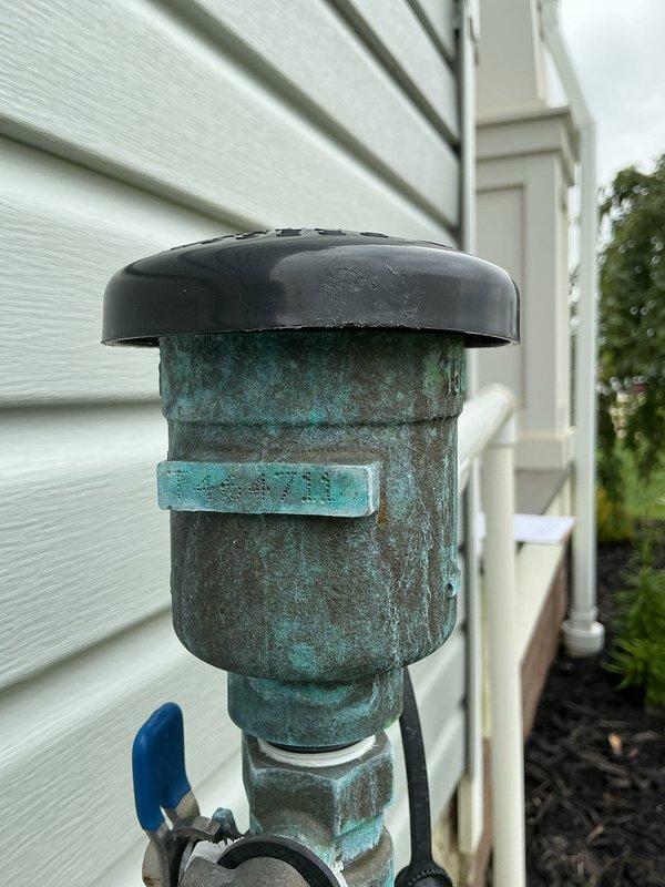 Performed annual backflow prevention device testing on irrigation system as required by municipal water authority. Inspected RPZ (Reduced Pressure Zone) backflow preventer assembly mounted on exterior wall, noting significant oxidation and patina on brass components. Conducted standard test procedures including check valve functionality, relief valve operation, and differential pressure measurements. Verified proper operation of test cocks and shutoff valves. Documented all test results and completed municipal compliance certification form for submission to city water department. Unit passed inspection and remains in acceptable working condition despite exterior corrosion. Photographed installation for service records.