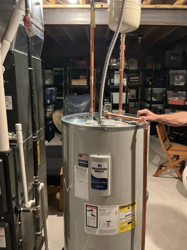 Installed a new 50-gallon Bradford White electric water heater with expansion tank in basement utility area. Completed all necessary copper piping connections, installed expansion tank, attached emergency shut-off tag, and staged unit with water heater installation kit. System tested and confirmed operational upon completion.