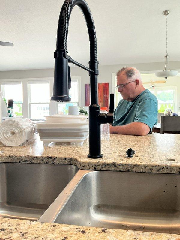 Completed kitchen faucet replacement, removing existing fixture and installing new Delta model matte black pull-down faucet with spring-style design and flexible spray head. Disconnected water supply lines, removed old faucet assembly and mounting hardware from granite countertop with double-basin undermount sink. Installed new faucet deck plate, secured mounting hardware, connected hot and cold water supply lines, and attached flexible hose assembly. Tested water flow and spray functions, checked all connections for leaks, and verified proper operation of pull-down mechanism and spray head settings.