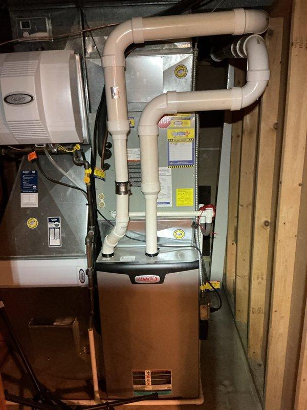 Completed installation of new A/C system with evaporator coil integrated with existing Lennox furnace in basement utility area. System includes properly routed white PVC condensate drainage lines, professional ductwork connections with insulation, and all electrical connections to manufacturer specifications for optimal performance and efficiency.