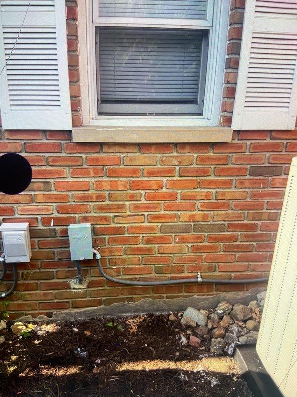 Completed second phase of split system air conditioning installation including outdoor condensing unit mounted on exterior brick wall with proper electrical disconnect and indoor evaporator coil integrated with existing furnace system. All refrigerant lines, condensate drainage, and electrical connections installed per manufacturer specifications with system tested and operational.