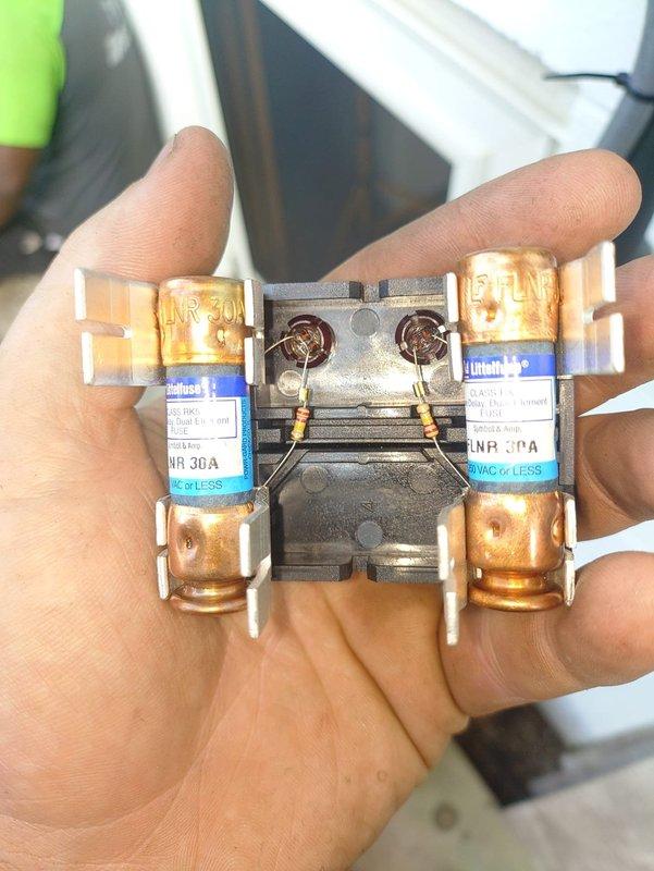 Completed second phase of air conditioning and coil installation. Installed new outdoor condensing unit with R-454B refrigerant system, including proper refrigerant line connections with service valves and brass fittings. Replaced dual 30-amp Limitron fuses in disconnect contactor to ensure proper electrical protection for the system. Verified all refrigerant lines are properly routed and insulated, with unit positioned on protective pad base with proper clearances. System components are operational and ready for startup procedures.