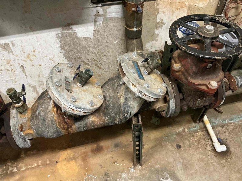 Provided estimate for replacement of 20+ year old 5-ton geothermal heat pump system that is no longer cooling. Assessed existing ground-source unit, air handler, and associated ductwork in mechanical room. Documented heavily corroded and deteriorated ground loop valves showing extensive rust and aging infrastructure. Recommended complete system replacement due to age and condition of equipment.