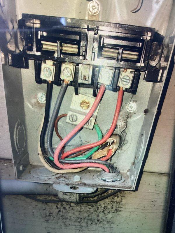 Completed scheduled cooling maintenance visit on 13-year-old HVAC system. Inspected electrical disconnect panel and identified signs of age-related wear, heat discoloration, and charring near wire entry points at the base of the enclosure. Examined internal wiring connections, terminal screws, and bus bar assembly for proper contact and potential safety concerns. Performed necessary electrical connection assessment and documented condition of disconnect mechanism and associated wiring for maintenance records.