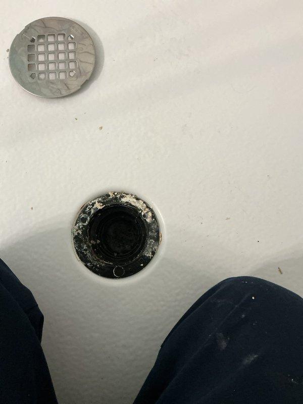 Responded to drain pipe maintenance call for shower in 40-year-old home where previous repair from two years ago had failed. Upon inspection, found bathtub drain assembly showing significant buildup and discoloration around lower drain fitting, with debris accumulation affecting proper drainage. Accessed crawlspace area to inspect drain line routing and connections through floor structure. Cleared obstruction from shower drain, removed accumulated debris and buildup from drain fittings, and verified proper water flow through drain system. Tested drain operation to ensure complete resolution of drainage issue.