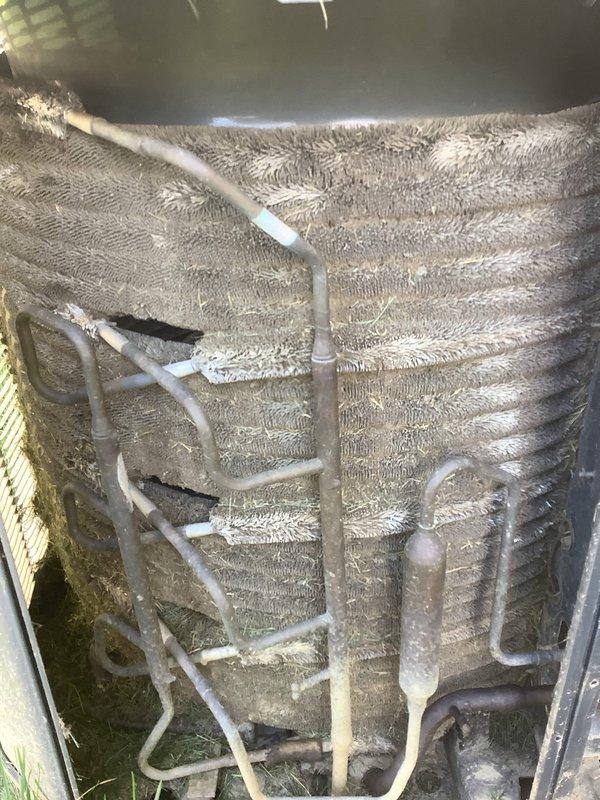Responded to service call for non-functioning thermostat on 15-year-old air conditioning system. Upon inspection, accessed outdoor condensing unit and documented internal components including evaporator coil assembly with aluminum fins showing normal weathering and operational refrigerant lines. Examined electrical components within unit, noting capacitor condition with visible corrosion and multiple wire connections secured with wire nuts. Unit exterior displayed typical age-related wear with dirt accumulation and minor surface rust on metal components consistent with outdoor installation. Photographed internal configuration for service records. System components assessed for proper operation related to thermostat malfunction complaint.