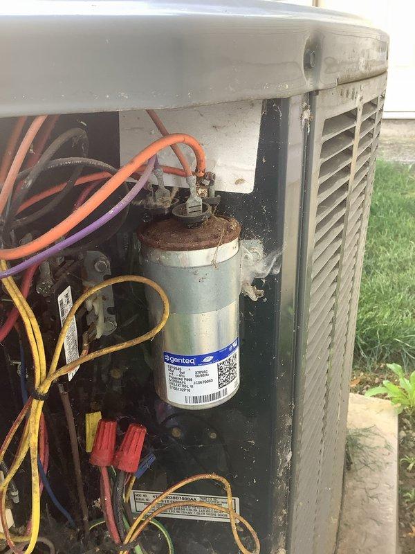 Responded to service call for non-functioning thermostat on 15-year-old air conditioning system. Upon inspection, accessed outdoor condensing unit and documented internal components including evaporator coil assembly with aluminum fins showing normal weathering and operational refrigerant lines. Examined electrical components within unit, noting capacitor condition with visible corrosion and multiple wire connections secured with wire nuts. Unit exterior displayed typical age-related wear with dirt accumulation and minor surface rust on metal components consistent with outdoor installation. Photographed internal configuration for service records. System components assessed for proper operation related to thermostat malfunction complaint.