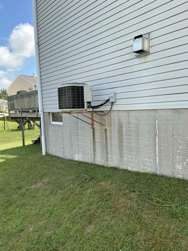 Completed estimate for replacement of residential air conditioning system. Existing outdoor condenser unit is 15+ years old and mounted on exterior wall with metal brackets, connected to indoor furnace system located in basement. Evaluated current HVAC configuration including electrical disconnect, conduit routing, and ductwork connections to provide replacement options for aging cooling system.