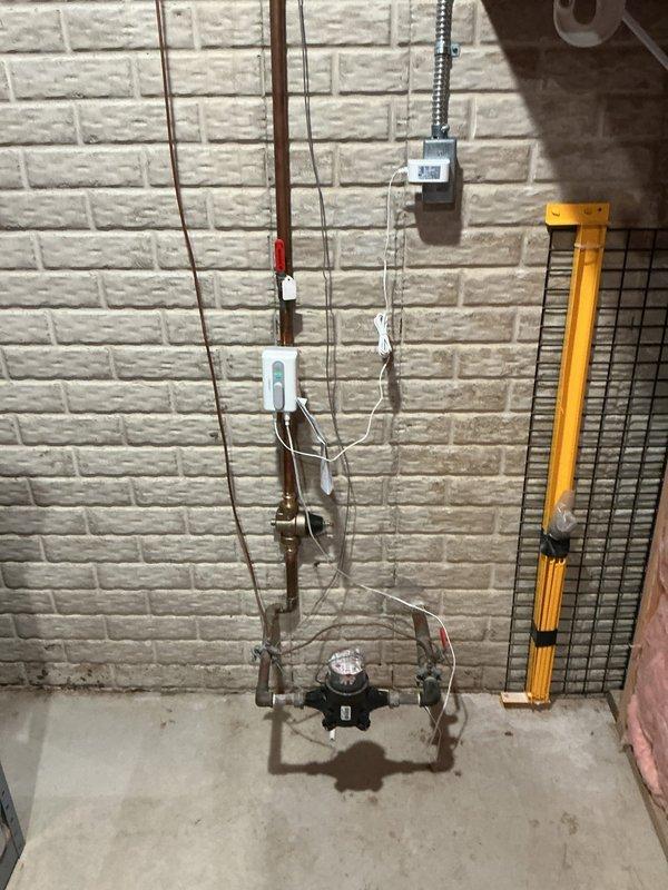 Responded to complaint of loud buzzing noise from pressure regulator valve. Inspected pressure reducing valve, expansion tank, and associated plumbing components installed in April 2024. Verified system pressure readings at exterior gauge and examined interior plumbing assembly including copper supply lines, flow control devices, and mounting hardware. Documented current conditions of pressure regulation system and water supply infrastructure with photographs for service records.