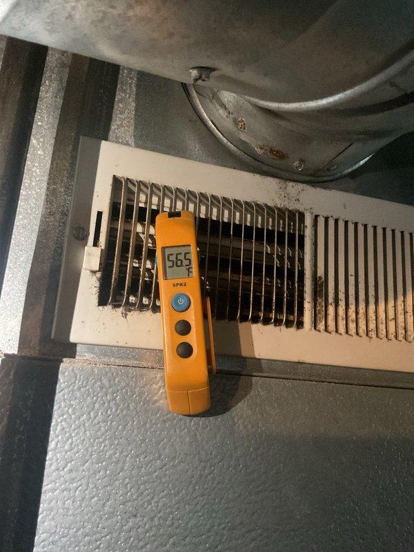 Completed MVP cooling maintenance visit on 15-year-old HVAC system. Performed system diagnostics using digital measurement tools, recording airflow readings of 665 CFM at supply register. Inspection revealed significant dust and debris accumulation on vent louvers and visible surface oxidation on ductwork. Observed heat-related discoloration and oxidation patterns on condensate drain pan, indicating extended thermal exposure consistent with system age. Documented equipment condition with photographic evidence for maintenance records.