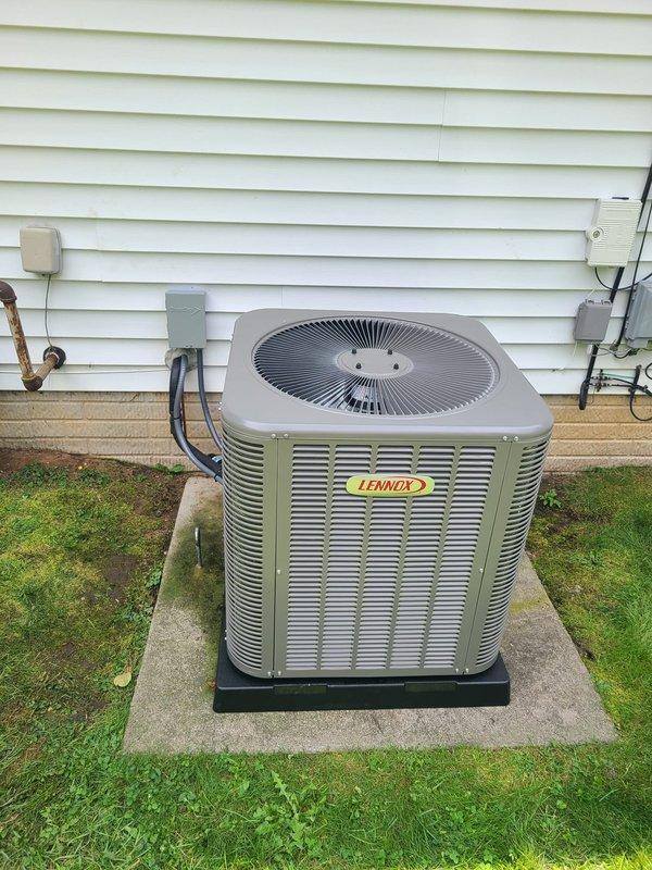 Completed installation of Lennox air conditioning system with evaporator coil as part of second-phase HVAC replacement. Installed outdoor condensing unit on concrete pad with proper leveling and vibration isolation, connected refrigerant lines with appropriate insulation (gray and black foam wrapping), installed service valves with R-410A refrigerant charging ports, and completed electrical disconnect and conduit work. System tested and verified operational with all connections secure and properly sealed.