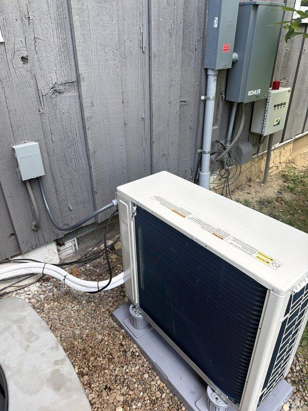 Completed installation of single-head mini-split system at residential property. Mounted outdoor condenser unit on concrete pad with proper clearances, installed indoor air handler below window, and ran refrigerant lines with insulation along exterior wall. Connected electrical service with appropriate disconnect, tested system operation, and verified proper cooling performance upon startup.