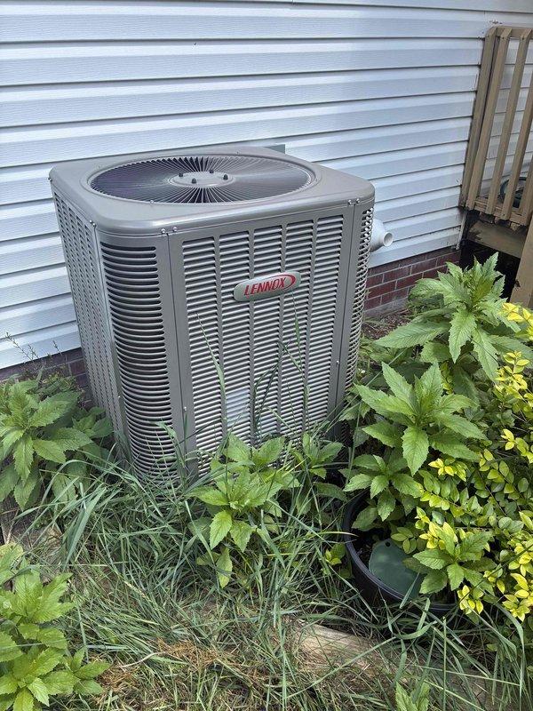 # HVAC Maintenance - Cooling

Completed scheduled MVP cooling maintenance visit on 1-year-old Lennox condensing unit. Removed access panel and inspected internal electrical components including dual capacitors, contactors, and associated wiring connections. All electrical connections were verified secure with proper wire routing observed throughout the system. Capacitors showed no signs of bulging or leakage, indicating proper operation within expected parameters for equipment age.

Examined outdoor unit positioned on concrete pad with noted vegetation encroachment around base and sides of condenser. Exterior coil grille and top fan guard inspected and found intact with no physical damage. Unit maintained adequate clearance from structure despite surrounding landscaping requiring monitoring for future airflow considerations.

System operational and functioning as designed. All components within normal operating specifications for routine preventive maintenance service.