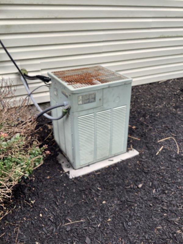Responded to no cooling complaint on 20-year-old air conditioning system. Found outdoor condenser unit attempting to start but failing to run, with fan motor running excessively hot. Upon inspection, identified failed condenser fan motor and heavily corroded top grill assembly with significant rust damage affecting unit operation. Diagnosed electrical issue preventing compressor from engaging properly while fan motor was overheating due to mechanical failure.
