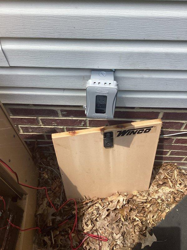 Replaced battery in Winco backup generator system and installed dedicated exterior weatherproof circuit with outlet for trickle charger connection. Wired new circuit from main electrical panel through exterior wall, mounted weatherproof enclosure on siding above brick foundation, and established proper connection to generator charging system to maintain battery health during standby periods.