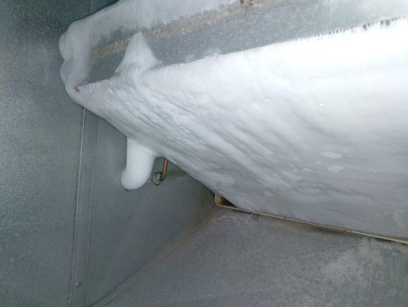 Responded to service call for 10-year-old whole-house AC system not cooling properly. Upon inspection, discovered evaporator coil completely frozen with extensive ice buildup throughout the unit, indicating restricted airflow or low refrigerant charge. Documented frost accumulation on coil assembly and surrounding components. Assessed outdoor condensing unit and associated refrigerant lines at exterior of property. System required defrost cycle completion before further diagnostic testing could be performed to determine root cause of freezing condition, which may include dirty air filter, blocked return air, low refrigerant levels, or failed blower motor.