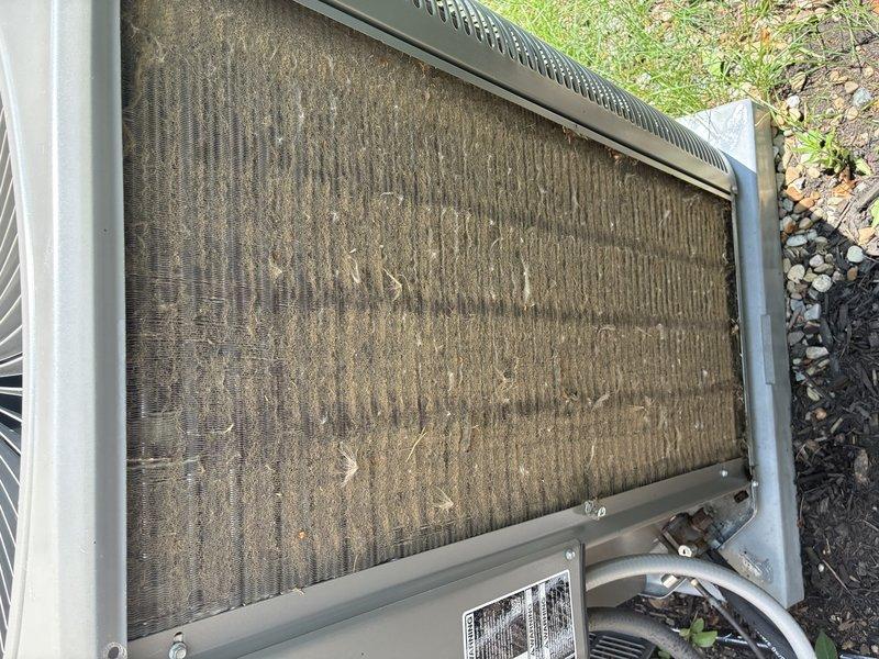 Completed MVP recurring cooling maintenance visit on residential HVAC system. Inspected indoor air handler and found heavily soiled air filter with significant accumulation of dust, dirt, fibers, and debris throughout pleated media, indicating extended operation without replacement. Removed and replaced contaminated filter to restore proper airflow and system efficiency. Performed exterior inspection of condenser unit and observed substantial dirt and debris buildup on coil surfaces with visible vertical flow patterns and contamination. Cleaned condenser coils to remove accumulated outdoor particulates and restore heat transfer capability. Verified proper system operation following maintenance procedures.