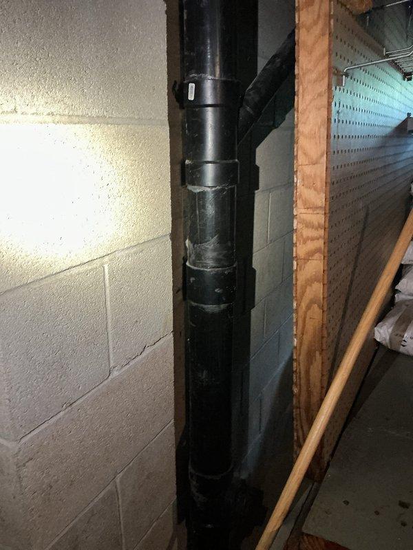 Installed new utility sink in garage where no previous plumbing existed. Ran supply and drain lines through wall from basement utility area, connecting to existing plumbing infrastructure visible in exposed ceiling joists. Completed rough-in plumbing work including copper supply lines with shutoff valves and PVC drainage system routed along foundation wall to tie into main drain stack.
