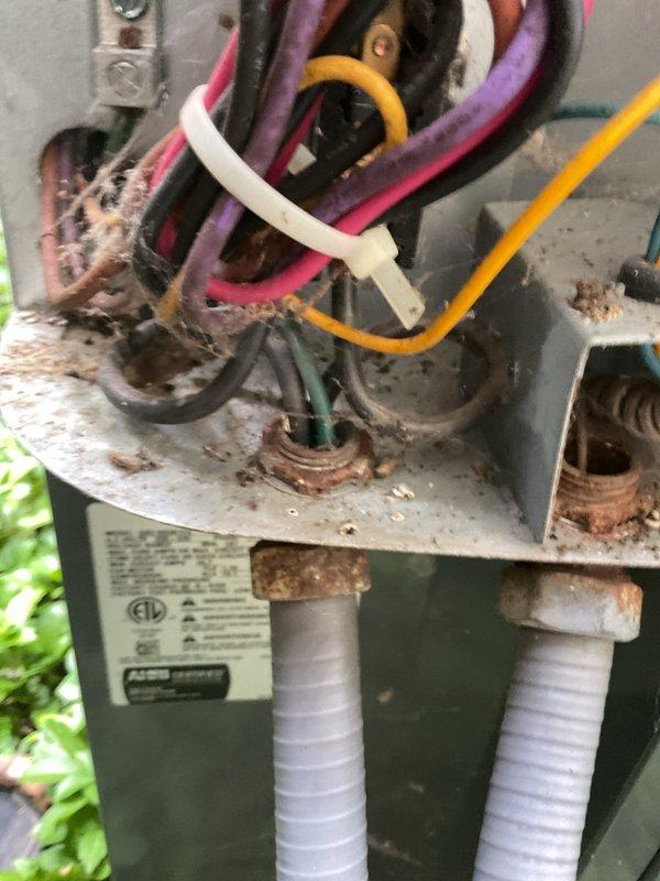 Responded to service call for AC system malfunction with thermostat incorrectly switching to heat mode and previous condenser coil freeze-up. Upon arrival, inspected outdoor condensing unit and found evidence of moisture accumulation on components, though coil was not actively frozen at time of inspection. Observed outdoor unit showing significant weathering, corrosion, and rust on electrical connections and housing, indicating extended exposure to environmental elements. Documented condition of equipment including deteriorated wiring connections, corroded terminals, and aging electrical components that may be contributing to system control issues. The thermostat reversing valve control circuit requires further diagnostic evaluation to determine root cause of heating mode activation during cooling operation, as initial inspection suggests potential wiring degradation or control board malfunction affecting system operation.