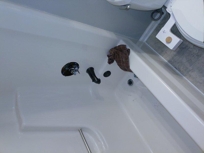 Responded to service call for dripping shower in 1970s-era home. Upon inspection, diagnosed faulty tub spout and shower valve assembly requiring replacement. Disassembled existing drain components and removed deteriorated gaskets and seals. Accessed shower valve through wall opening to evaluate internal plumbing connections and copper supply lines. Replaced worn valve cartridge, installed new tub spout with proper escutcheon plate, and reassembled drain assembly with new gaskets to eliminate leak. Tested system for proper water flow and verified complete cessation of dripping. All components secured and operational upon completion.
