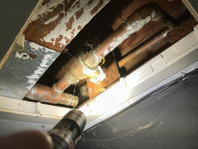 Responded to service call for broken outdoor spigot on 98-year-old residential property with blue wood siding. Upon arrival, assessed existing hose bib which had failed due to age and deterioration. Accessed interior copper supply lines through ceiling/wall cavity to evaluate connection points and verify no additional pipe damage or leaks in the aged plumbing system. Observed oxidized copper piping with existing foam insulation in confined space. Removed failed outdoor faucet assembly and prepared mounting surface on exterior wall. Installed new frost-free hose bib with appropriate wall penetration and secured mounting to ensure proper drainage angle. Connected new fixture to existing copper supply line, ensuring watertight seal at all connection points. Tested system for proper operation and verified no leaks at interior connections or exterior mounting point. Restored insulation around supply lines and sealed wall penetration. New spigot now fully operational with clear access above 