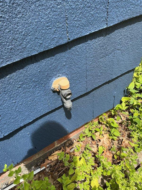 Responded to service call for broken outdoor spigot on 98-year-old residential property with blue wood siding. Upon arrival, assessed existing hose bib which had failed due to age and deterioration. Accessed interior copper supply lines through ceiling/wall cavity to evaluate connection points and verify no additional pipe damage or leaks in the aged plumbing system. Observed oxidized copper piping with existing foam insulation in confined space. Removed failed outdoor faucet assembly and prepared mounting surface on exterior wall. Installed new frost-free hose bib with appropriate wall penetration and secured mounting to ensure proper drainage angle. Connected new fixture to existing copper supply line, ensuring watertight seal at all connection points. Tested system for proper operation and verified no leaks at interior connections or exterior mounting point. Restored insulation around supply lines and sealed wall penetration. New spigot now fully operational with clear access above 