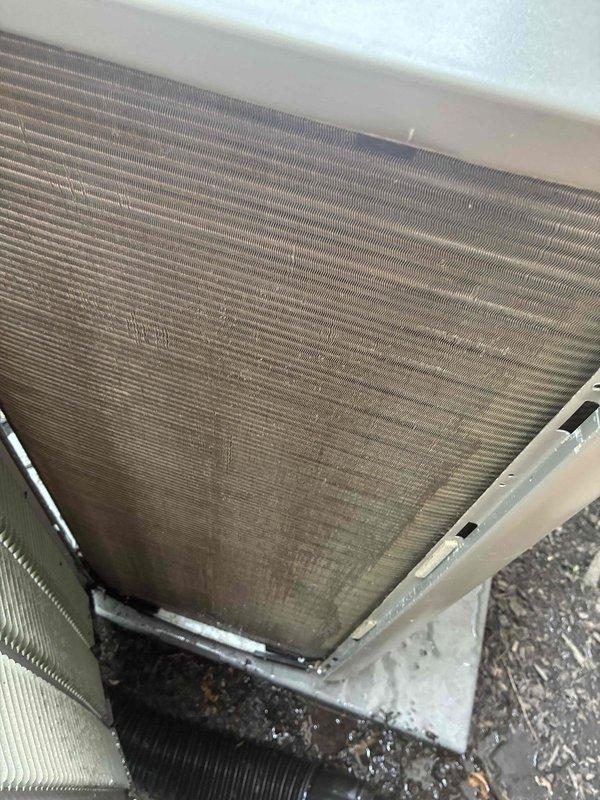 # HVAC Maintenance - Cooling Service

Performed comprehensive MVP cooling maintenance visit on residential HVAC system. Conducted thorough inspection of outdoor condenser unit, documenting significant accumulation of dirt, dust, and debris on condenser coil fins throughout the unit. The coil exhibited grayish-brown discoloration with heavy contamination buildup affecting heat transfer efficiency, though fins remained structurally intact without bending or damage. Noted organic debris and plant material at base of unit. 

Inspected indoor components in attic installation, including furnace cabinet and associated ductwork. Verified system configuration with dehumidifier integration. Documented equipment condition through photographic evidence for maintenance records. All structural components and connections found secure with no visible damage to cabinet, ductwork, or support systems.