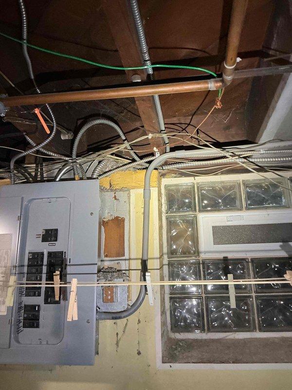 Responded to service call regarding low-hanging electrical wiring running between main residence and detached garage on property with approximately 98-year-old home. Conducted thorough assessment to determine wire function and operational status. Inspected exterior meter base, service entrance conductors, and associated junction boxes on house exterior. Traced wiring pathway from main electrical panel located in basement utility area through exterior wall penetration to garage structure. Verified circuit integrity by testing for voltage presence at multiple points along wire run. Examined main service panel and identified corresponding breaker positions. Determined wires were energized and actively supplying 120/240V power to garage subpanel for lighting and receptacle circuits. Assessed wire sag condition and evaluated support requirements per NEC standards. Documented existing installation with photographs showing meter configuration, main panel layout, and conduit routing. Provided 