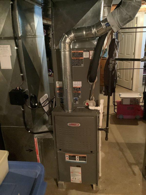 Completed installation of new Lennox air conditioning system including outdoor condenser unit and indoor evaporator coil. Outdoor condenser unit was positioned on composite pad against exterior wall with proper electrical disconnect and conduit connections to meet code requirements. Indoor evaporator coil was installed and integrated with existing Lennox furnace in basement utility area, with all necessary ductwork connections, condensate drain line, and refrigerant lines properly secured and tested for system operation.