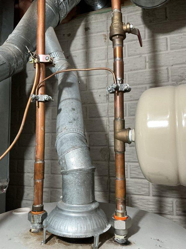 Responded to service call for leaking 10-year-old natural gas tanked water heater that had been shut off by homeowner. Upon inspection, confirmed active leak from aging Bradford White 50-gallon atmospheric vent unit (Model RG25OT6N). Assessed existing installation including venting system with galvanized flue pipe, copper supply lines, shut-off valves, and expansion tank mounted in basement utility area. Documented current system configuration and condition of associated plumbing components. Provided estimate for complete water heater replacement including removal and disposal of failed unit, installation of new comparable natural gas water heater with proper venting, connection to existing copper supply lines and gas piping, and verification of all safety controls and temperature/pressure relief valve operation. Customer available for scheduling between 9 AM and 5 PM with advance notification.