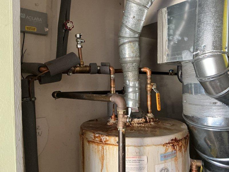 Replaced a non-functional tanked water heater that exhibited severe rust deterioration and corrosion throughout the unit, particularly concentrated at the base and lower third of the tank. Disconnected existing copper supply lines and vent ductwork, removed the failed unit, and installed a new water heater with proper code-compliant connections including hot and cold water lines, temperature and pressure relief valve, and gas supply connections. Tested all connections for leaks and verified proper operation of the new system.