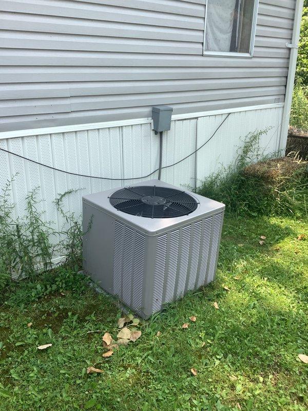 Completed HVAC system replacement estimate for mobile home installation. Assessed existing outdoor condensing unit positioned on ground-level pad adjacent to structure with electrical disconnect and conduit routing from exterior wall junction box. Evaluated interior return air grill and ductwork accessibility for complete system changeout specifications.