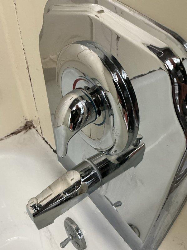 Removed existing two-handle shower valve and tub spout assembly from tiled shower enclosure. Accessed plumbing from rear access panel and cut copper supply lines, installing new ball valves to provide future isolation capability for the shower system. Installed new Moen single-handle Posi-Temp pressure-balancing shower valve, connecting to existing riser within wall cavity. Mounted chrome trim kit and single-handle control on valve body. Installed new chrome tub spout on copper stub-out. Fitted white remodel escutcheon plate over wall penetrations to conceal openings left by previous two-handle configuration. Applied silicone bead around perimeter of remodel plate to secure fixture and create water-resistant seal preventing moisture intrusion behind shower wall. Tested system for proper operation, temperature control, and verified no leaks at connections. Installation restored full shower and tub functionality with updated single-handle control system.