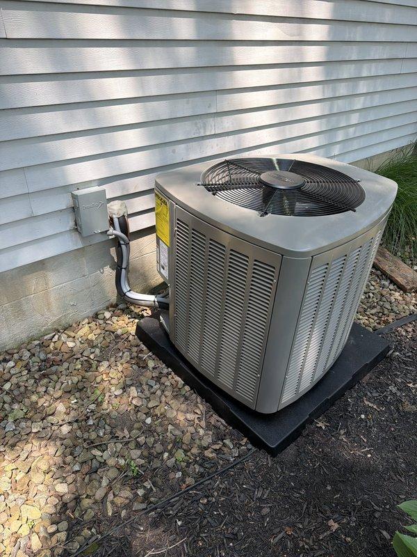 Completed installation of a 90% efficiency furnace and air conditioning system. The outdoor condenser unit was positioned on a protective pad with proper clearance from the building, including electrical disconnect box installation and refrigerant line connections. The furnace was installed with appropriate venting, gas line connections via brass fittings, and condensate drainage. Both units were set on vibration-dampening pads, all electrical connections were completed to code, and the system was tested for proper operation.